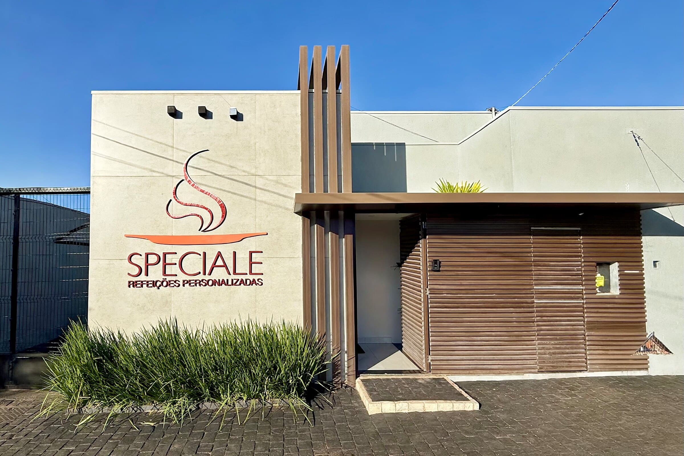 Fachada da Speciale em Uberlândia, com o letreiro Speciale Refeições Personalizadas e a entrada com ripas de madeira