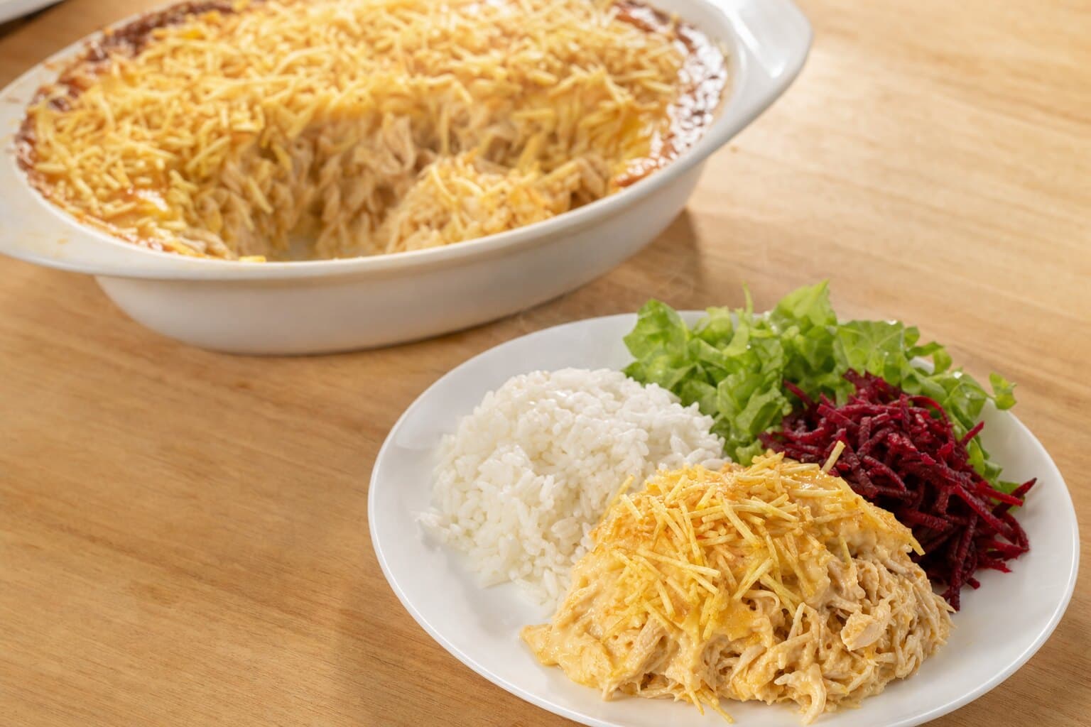 Fricassê de frango com batata palha servido com arroz e salada de alface e beterraba
